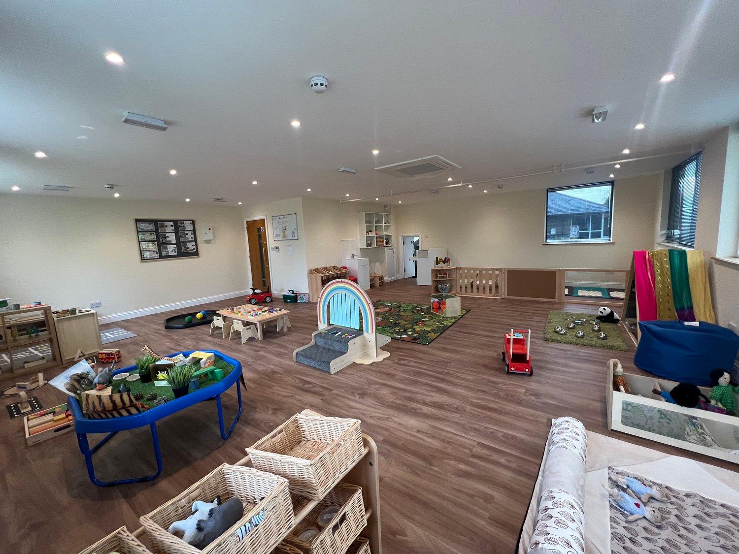 A bright nursery room with open-ended construction and role-play resources