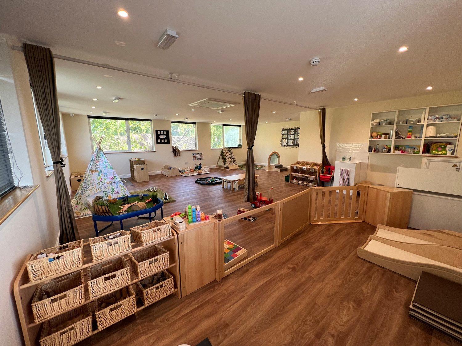 A prepared nursery room with low shelves, child-sized furniture, and defined play areas