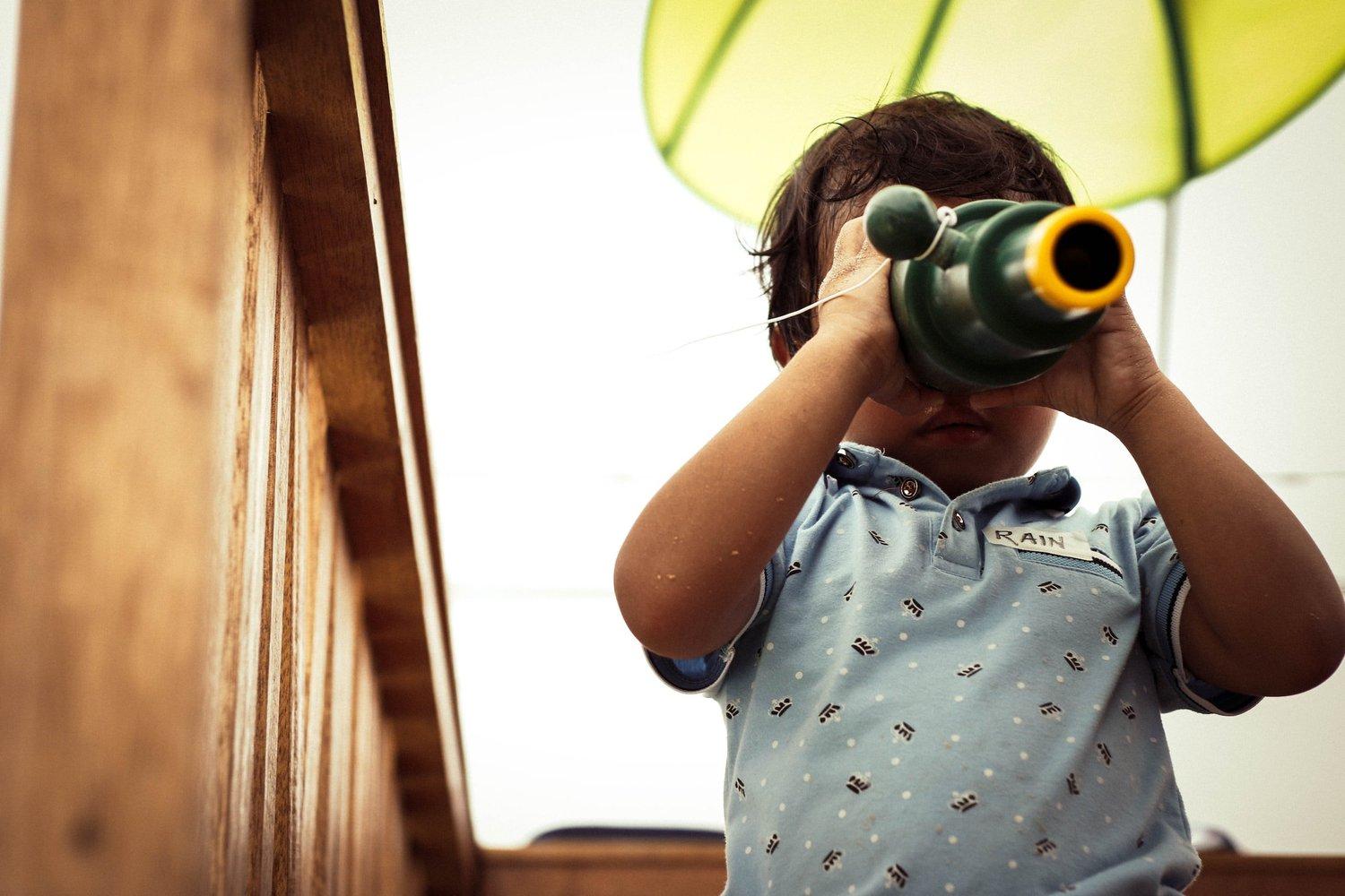 A young child exploring the world through a toy telescope